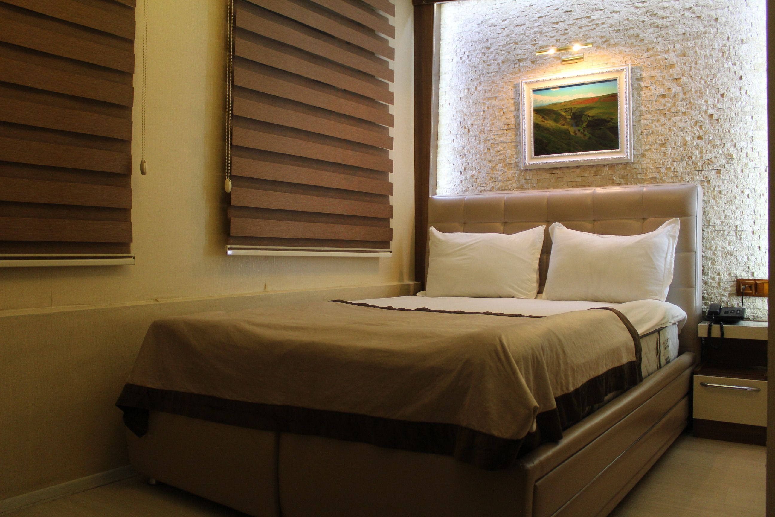 A bedroom with a bed, a nightstand, and a painting on the wall.