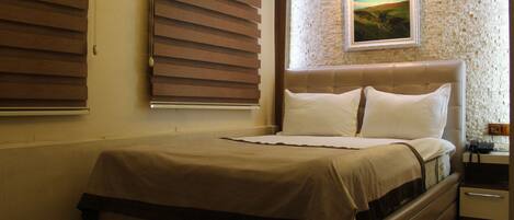 A bedroom with a bed, a nightstand, and a painting on the wall.