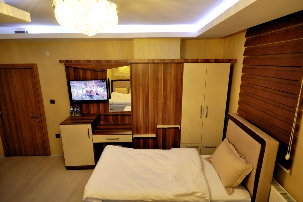A bedroom with a bed, a TV, a desk, and a wardrobe.