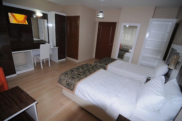 A bedroom with a bed, a desk, a chair, a wardrobe, and a mirror.