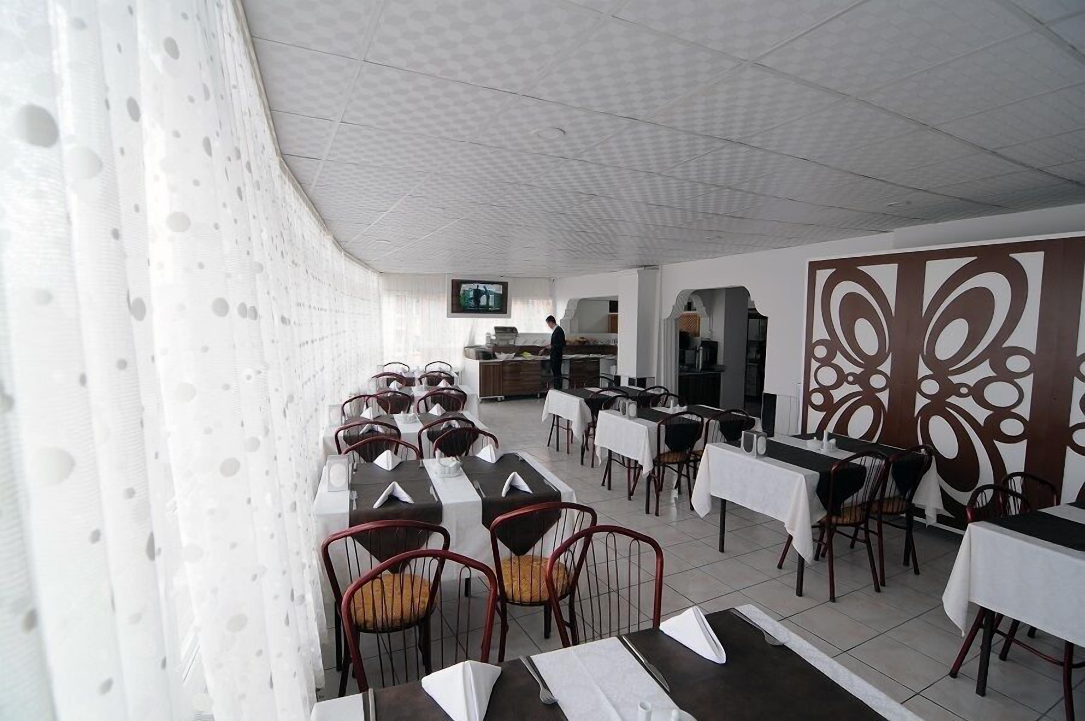 A restaurant with tables and chairs, a television screen, and a decorative wall.