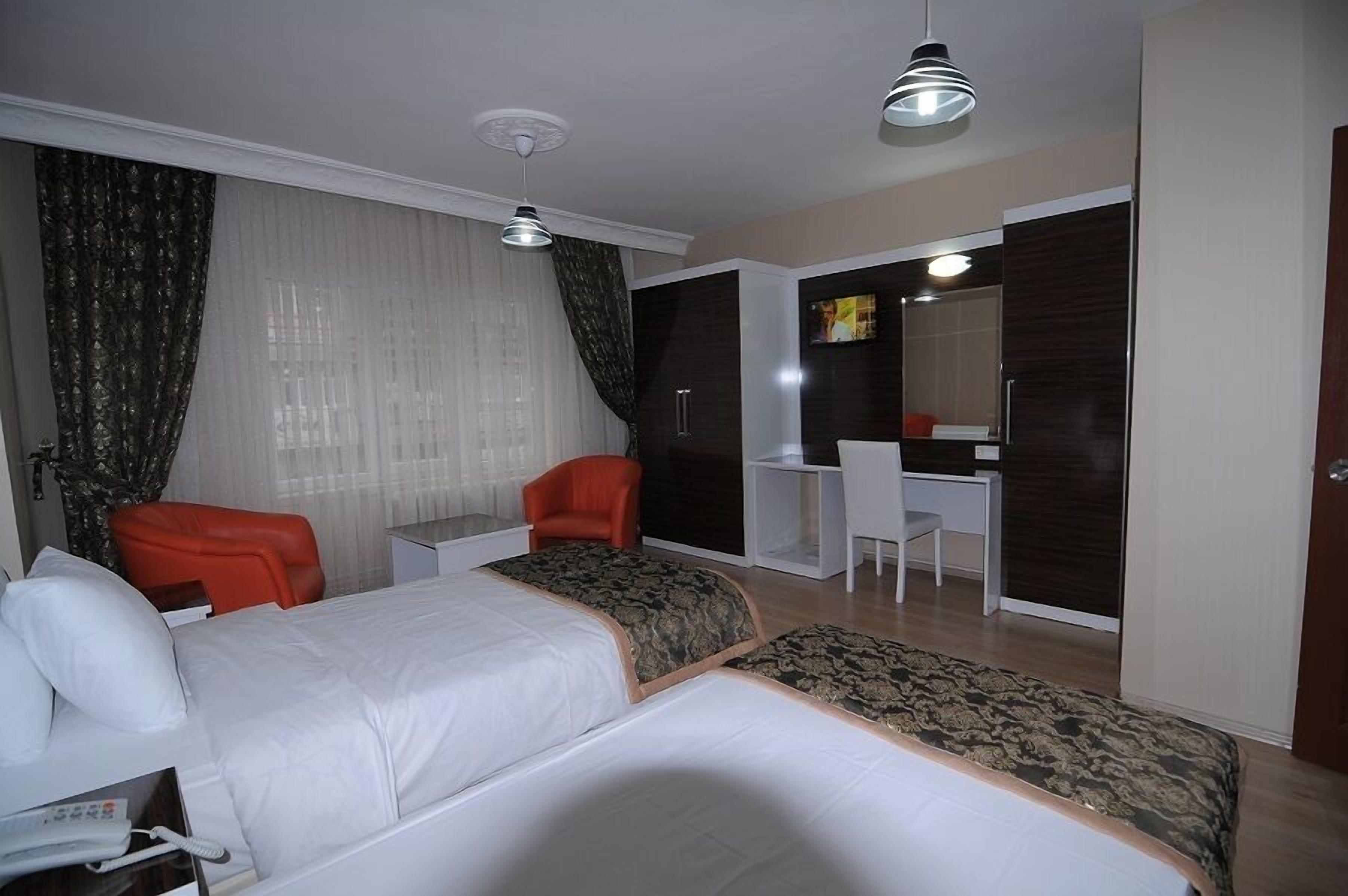 A hotel room with two beds, a desk, a chair, and a wardrobe.
