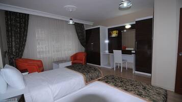 A hotel room with two beds, a desk, a chair, and a wardrobe.