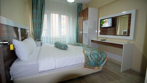 A hotel room with a bed, a TV mounted on the wall, a desk, and a window with curtains. - Kosk Hotel (Elazig)