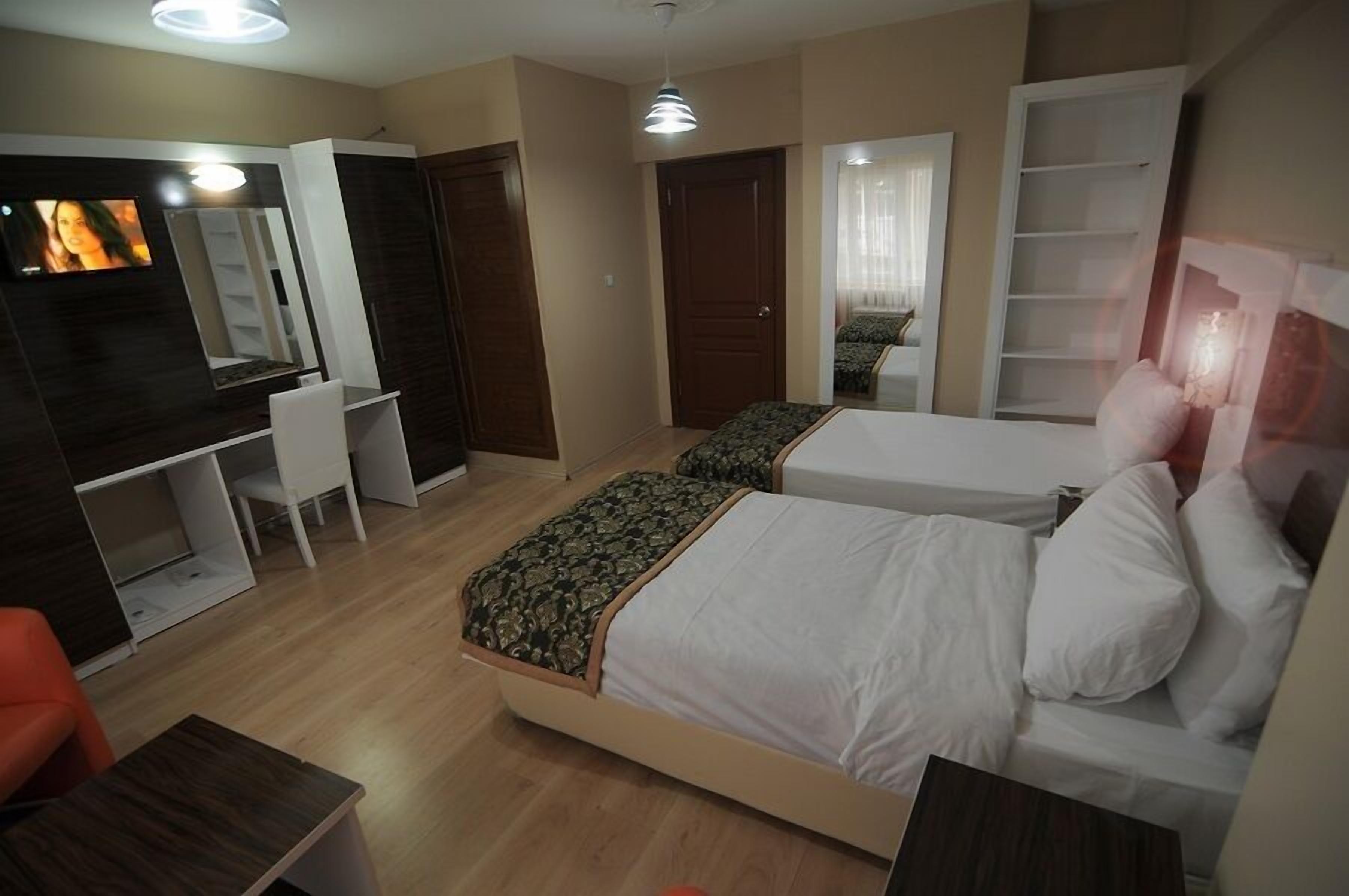 Una habitación de hotel con dos camas, un escritorio, una silla y un televisor.