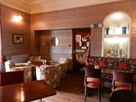 Un interior acogedor con papel tapiz estampado, una zona de bar de madera y diferentes disposiciones de asientos.