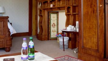 Ein Zimmer mit einem Holzschrank, einem Tisch mit zwei Flaschen sprudelndem Wasser und einem dekorativen Spiegel.
