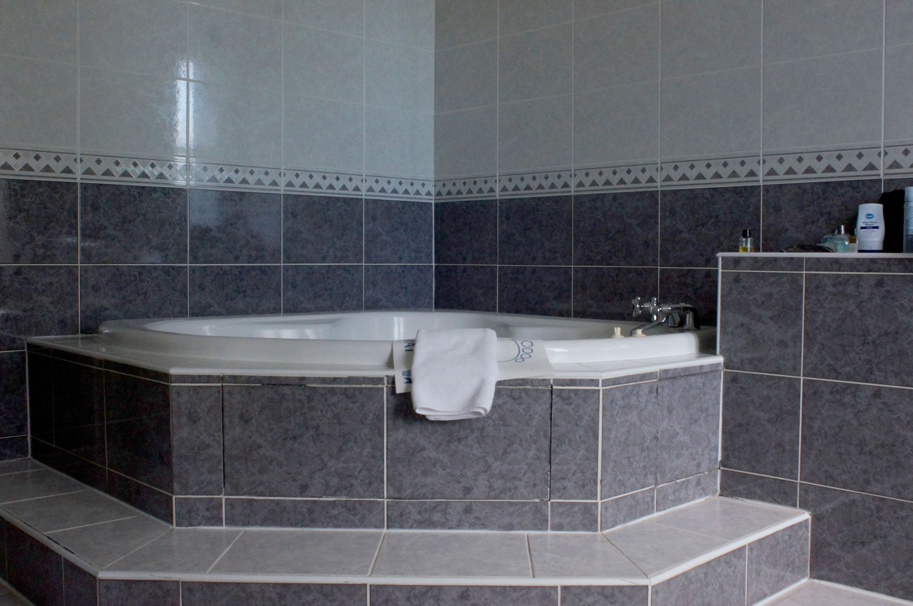 A modern bathroom with a freestanding bathtub, tiled walls, and a small shelf with toiletries.