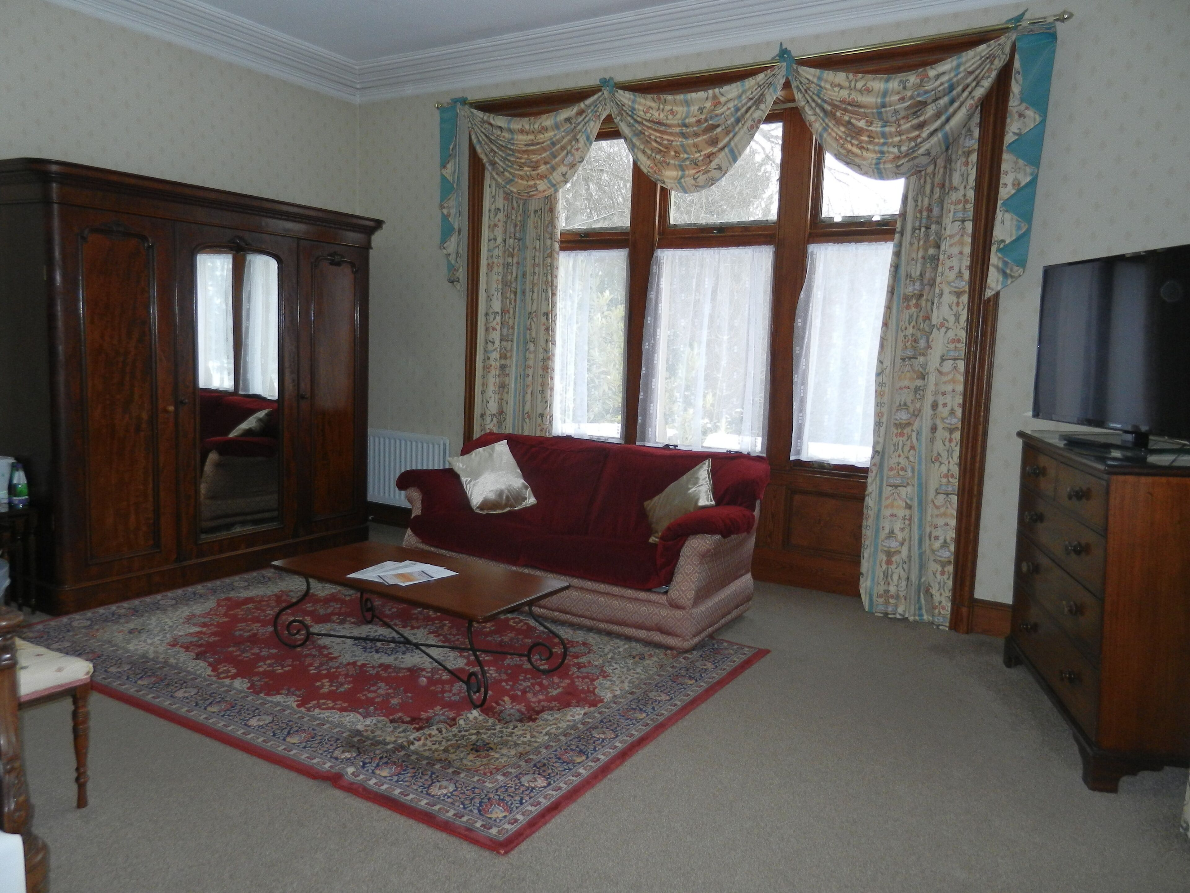A living room with a red sofa, wooden cabinet, and a television.