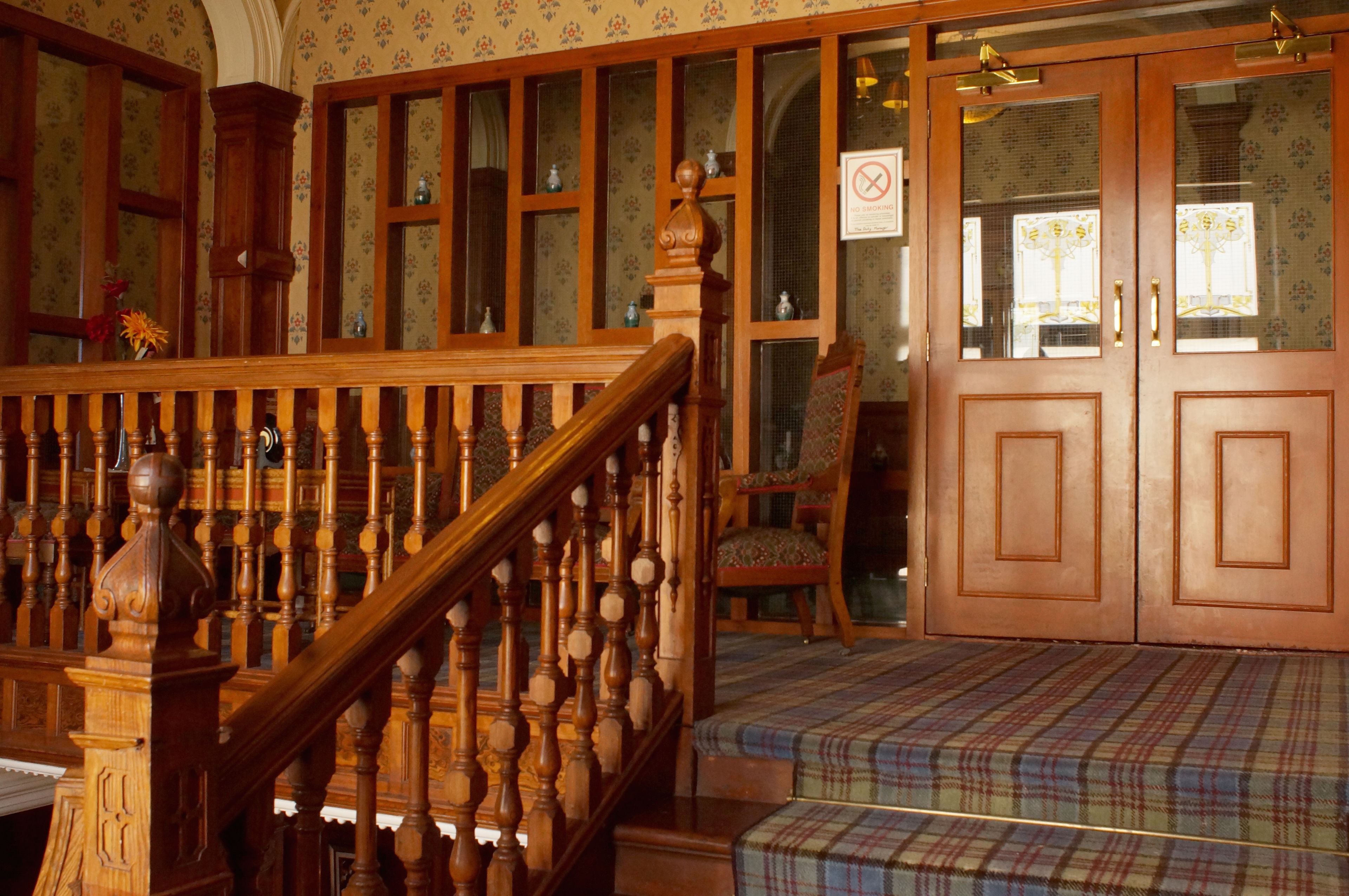 A staircase with wooden balusters, a plaid-patterned bench, and a door with a frosted glass panel.