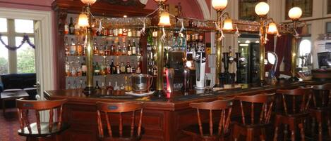 A bar area with wooden chairs, a bar counter, and a clock on the wall.