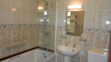 Un baño con ducha de vidrio, bañera, lavabo e inodoro.