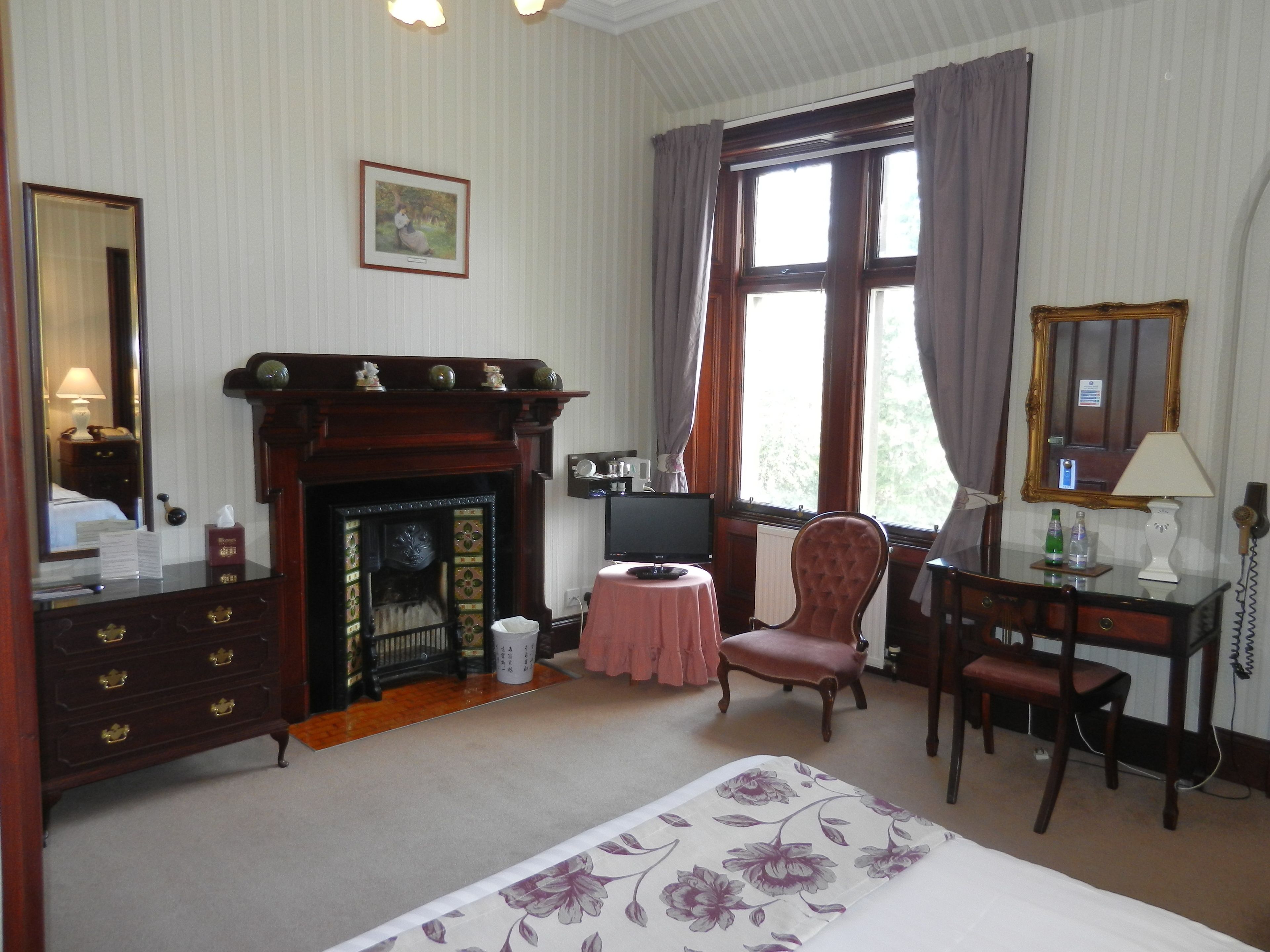 A room with a fireplace, a desk, a chair, and a bed.