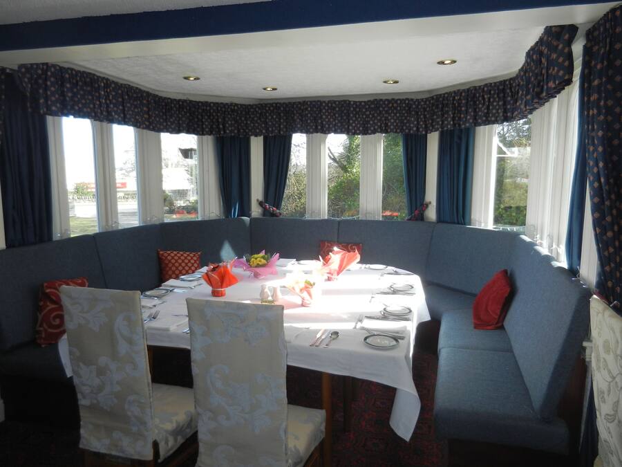 Een eetgedeelte met een ronde tafel gedekt voor vier personen, omringd door blauwe bekleding.
