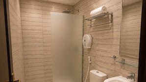 A bathroom with a shower, toilet, sink, and hand dryer.
