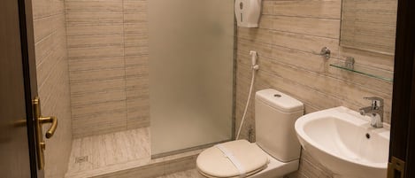 A bathroom with a shower, toilet, sink, and hand dryer.