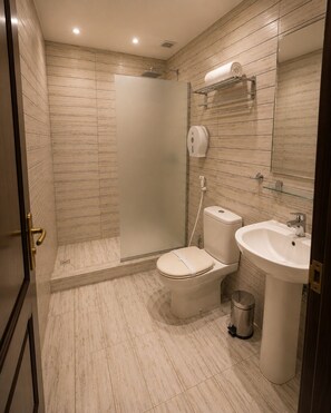 A bathroom with a shower, toilet, sink, and hand dryer. - Valencia Hotel (Cairo)