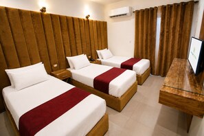 A hotel room with three beds, a wooden headboard, a TV, and an air conditioning unit. - Valencia Hotel (Cairo)
