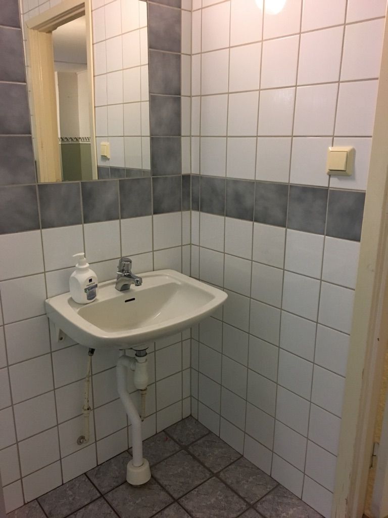 A bathroom with a white sink, mirror, and tiled walls.