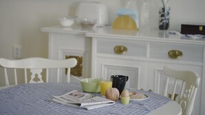 A dining table with a newspaper, a bowl, a glass of orange juice, a black mug, and a plate with food. - Hotell Östergyllen (Linkoping)
