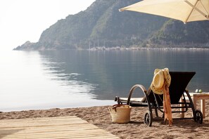 Un cadre idyllique au bord de la plage, avec une terrasse en bois, une chaise longue, un parasol et un panier en osier.