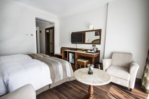 Une chambre d’hôtel avec un lit, un bureau, une chaise et une petite table.