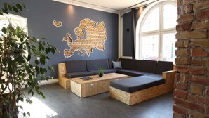 A modern living room with a sectional sofa, a wooden coffee table, and a large window. - Blue Doors Hostel KTV (Rostock)