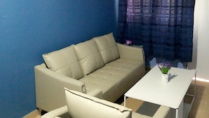 Una sala de estar con un sofá color beige, una mesa de centro blanca y una pared azul.
