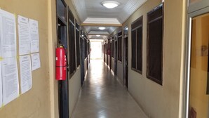 Un pasillo con puertas a ambos lados, un extintor de incendios en la pared y luces en el techo.