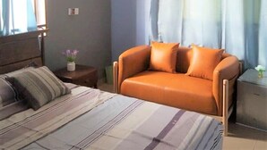 Un dormitorio con cama, sofá y cortinas.