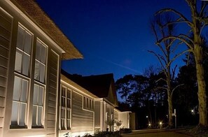 Una casa moderna con ventanas amplias e iluminación exterior al anochecer.