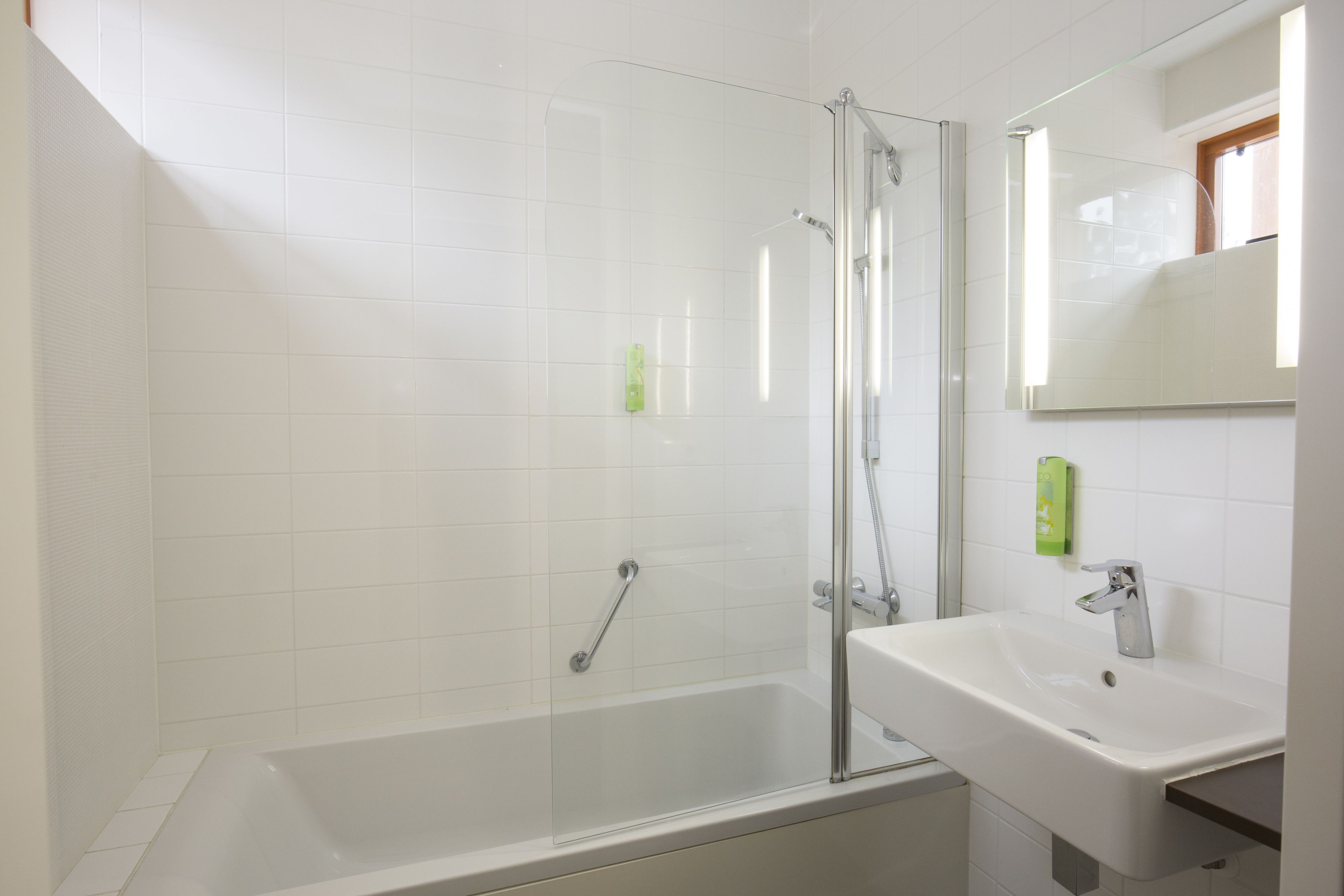 A modern bathroom with a glass-enclosed shower, a white sink, and a mirror above the sink.
