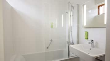 Een moderne badkamer met een douche met glazen wand, een wit wastafelmeubel en een spiegel erboven.