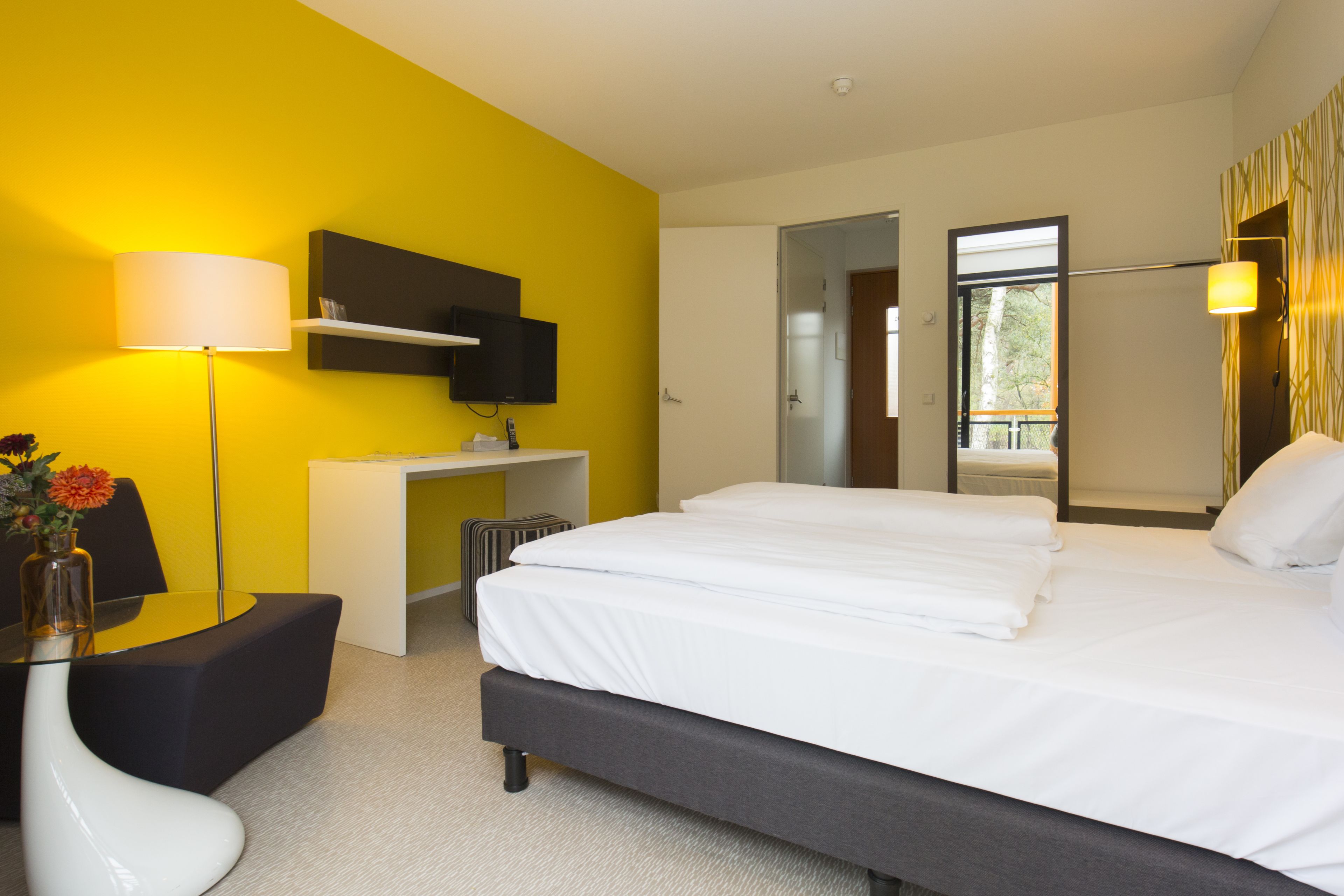 Een moderne hotelkamer met een groot bed, een bureau, een stoel en een televisie.
