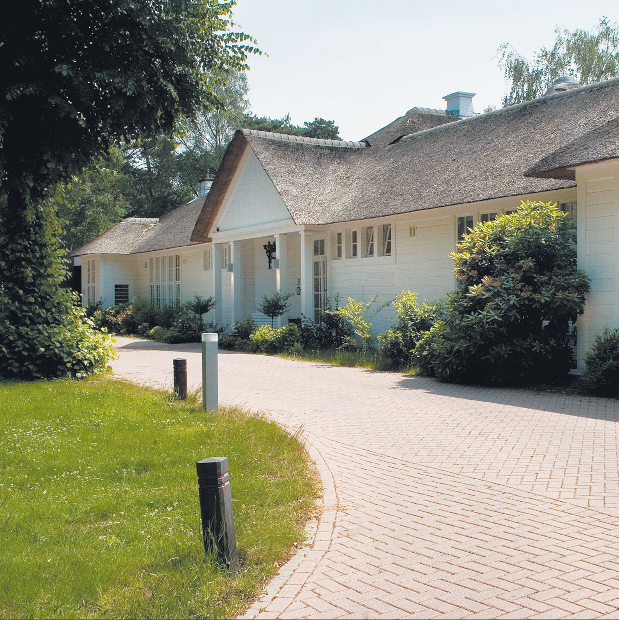Un bâtiment doté d’un toit de chaume, d’une allée pavée et d’une pelouse bien entretenue.