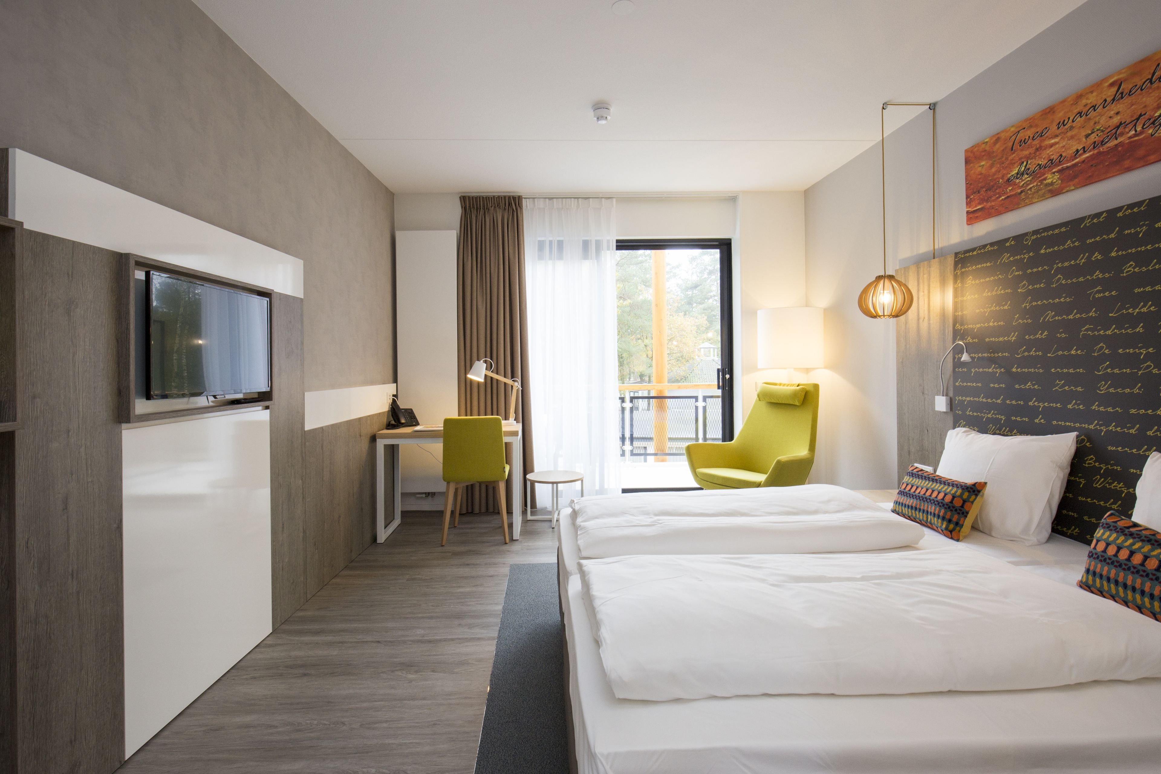 Een hotelkamer met een bed, een bureau, een stoel en een televisie.