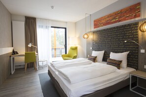 Habitación de hotel con una cama grande, un escritorio, una silla y vistas al exterior.
