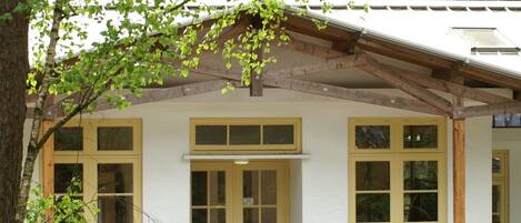 A building with a white exterior, a wooden roof, and multiple windows.