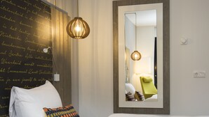 A hotel room with a large bed, a bedside lamp, a mirror, and a wall with a decorative pattern. - Landgoed ISVW (Leusden-Centrum)