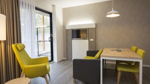 A modern dining area with a wooden table and chairs, a built-in TV, and a large window with curtains. - Landgoed ISVW (Leusden-Centrum)