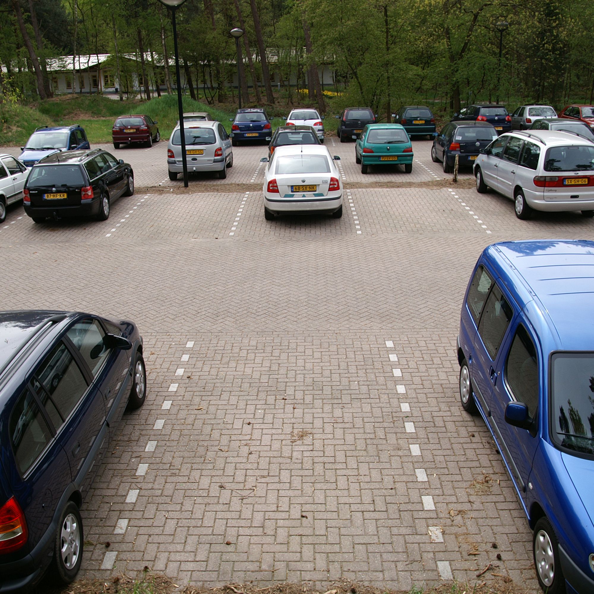 Un aparcamiento con varios coches estacionados en filas.