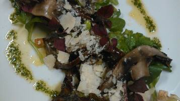 A plate of food with a variety of greens, mushrooms, and crumbled cheese.