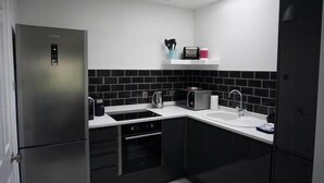A modern kitchen with a built-in oven, a stovetop, a sink, and a microwave. - 3 Summertown Court (Oxford)