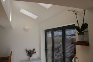 A modern interior with a skylight, a potted orchid, and a sliding glass door leading to an outdoor area.