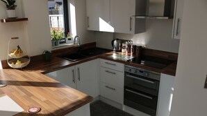 A modern kitchen with wooden countertops, stainless steel appliances, and white cabinetry. - Luxury Victorian Garden Apartment (Bristol)