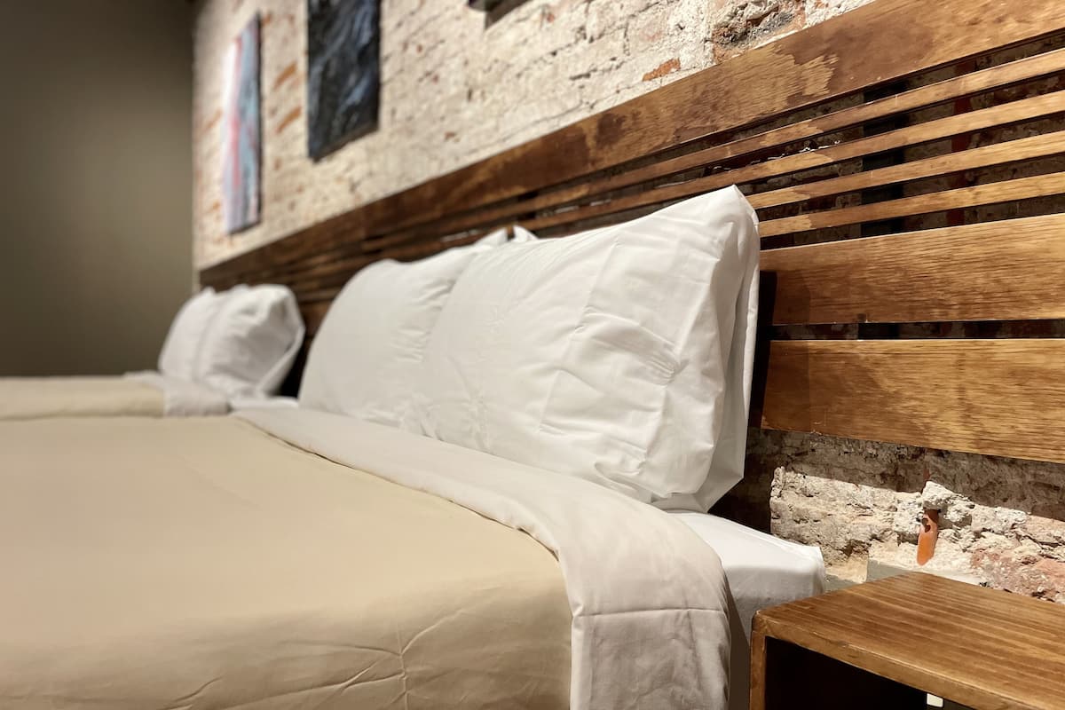 Una cama con ropa blanca, un cabecero de madera y una mesita de noche de madera.