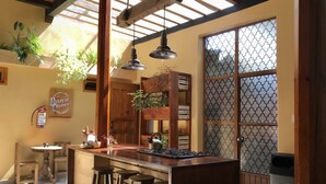 Una cocina con una isla central, taburetes de madera, lámparas colgantes y un ventanal con vidrio decorativo.