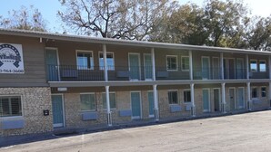 Un motel de dos pisos con fachada de piedra, varias habitaciones con puertas azules, y un letrero que anuncia Horseshoe Riverside Lodge.