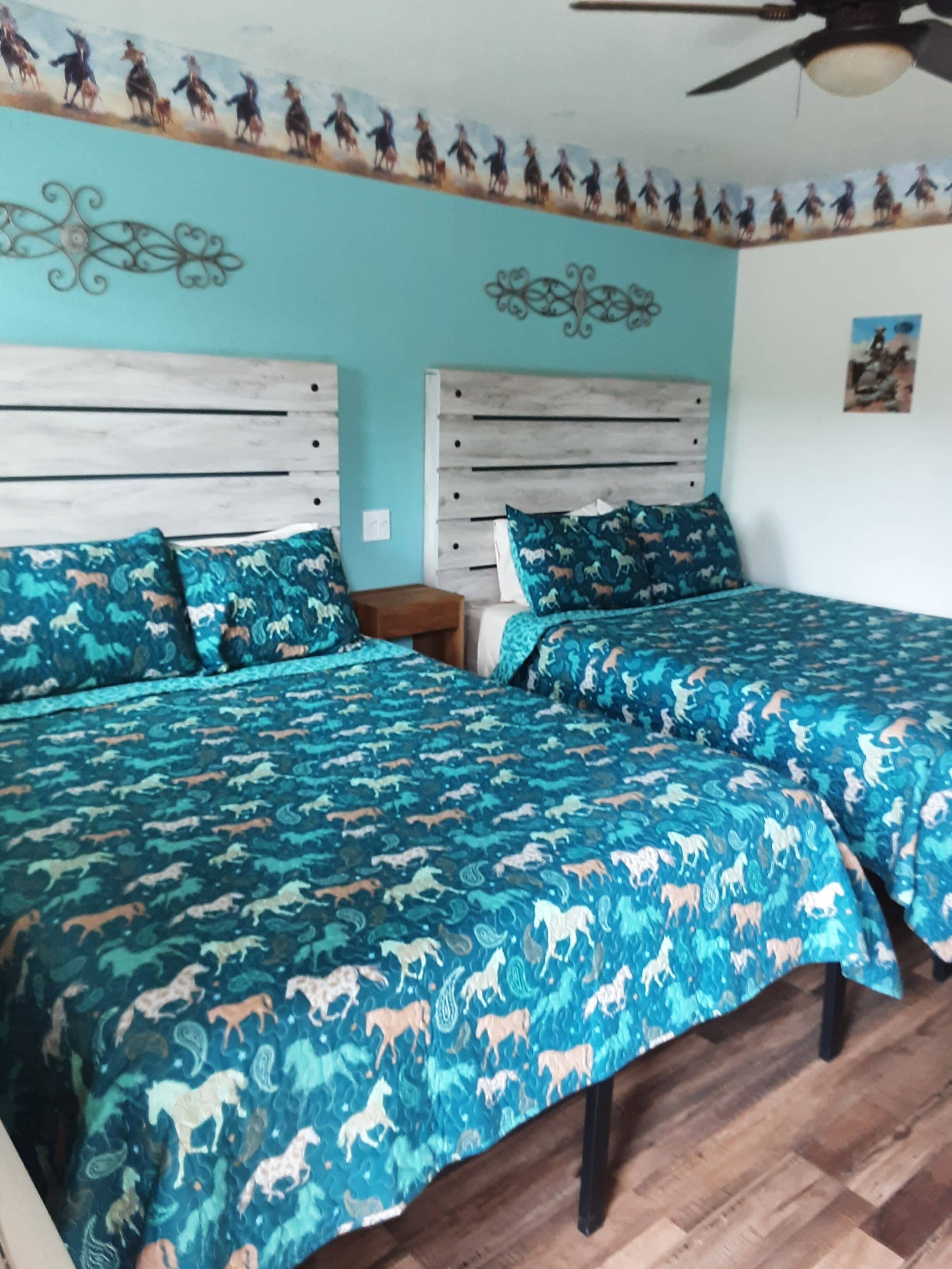 A bedroom with two beds, a wooden headboard, a nightstand, and a ceiling fan.