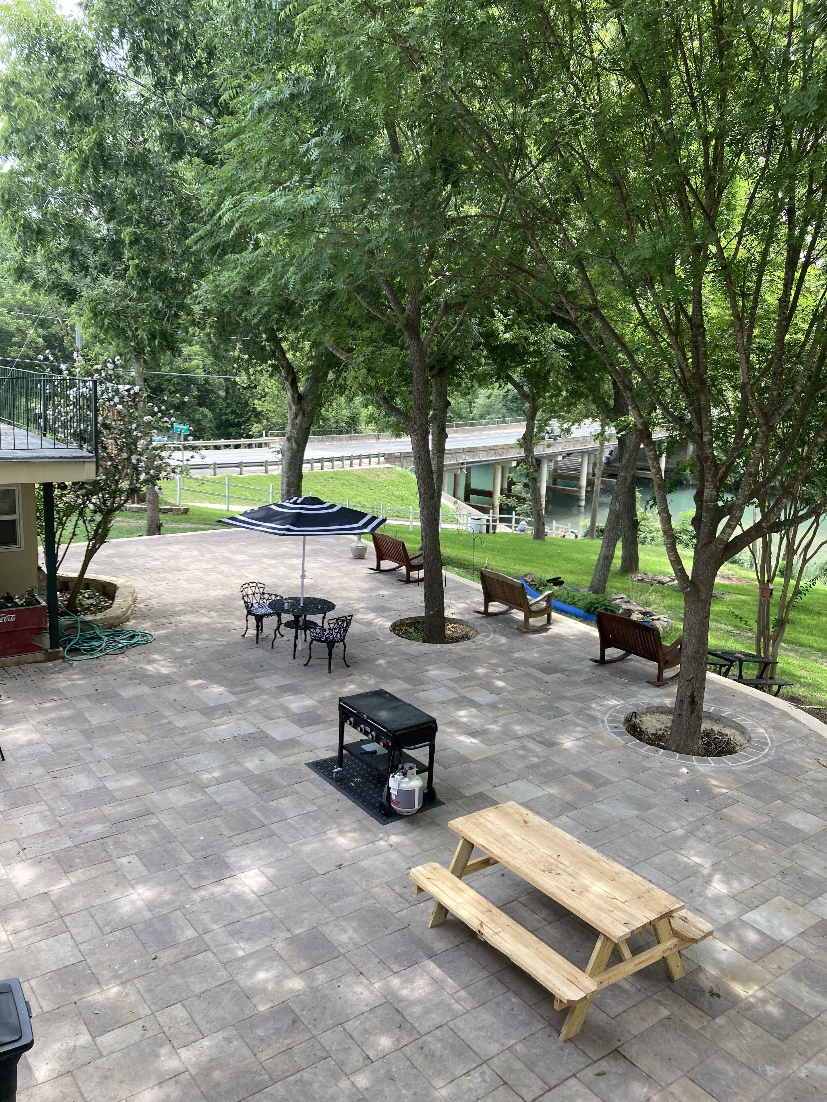 Une terrasse dallée avec des tables de pique-nique, un barbecue et des sièges d’extérieur.